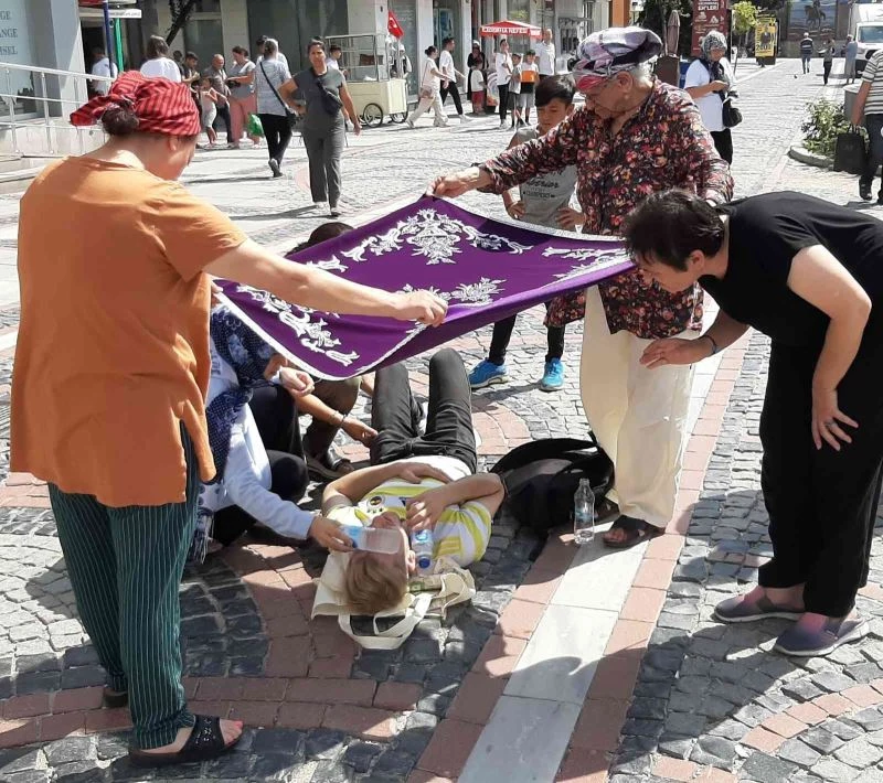 KADINLAR YERDE YATAN YARALIYI ÖRTÜ İLE GÜNEŞTEN KORUDU